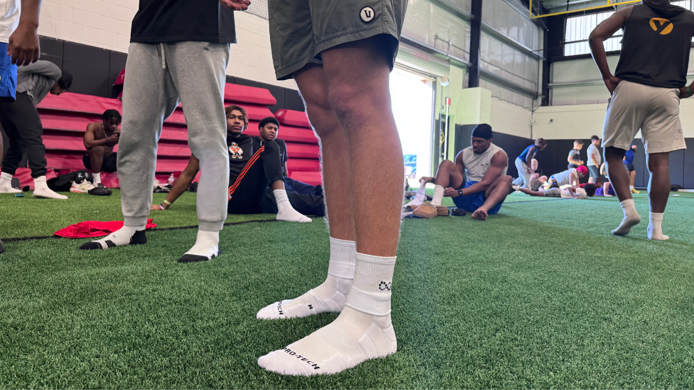 People on a sports field with focus on feet wearing white pro-tech prime socks.